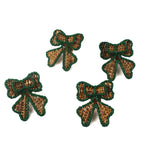 Set of four green-trimmed rattan bow napkin rings arranged on a white background.