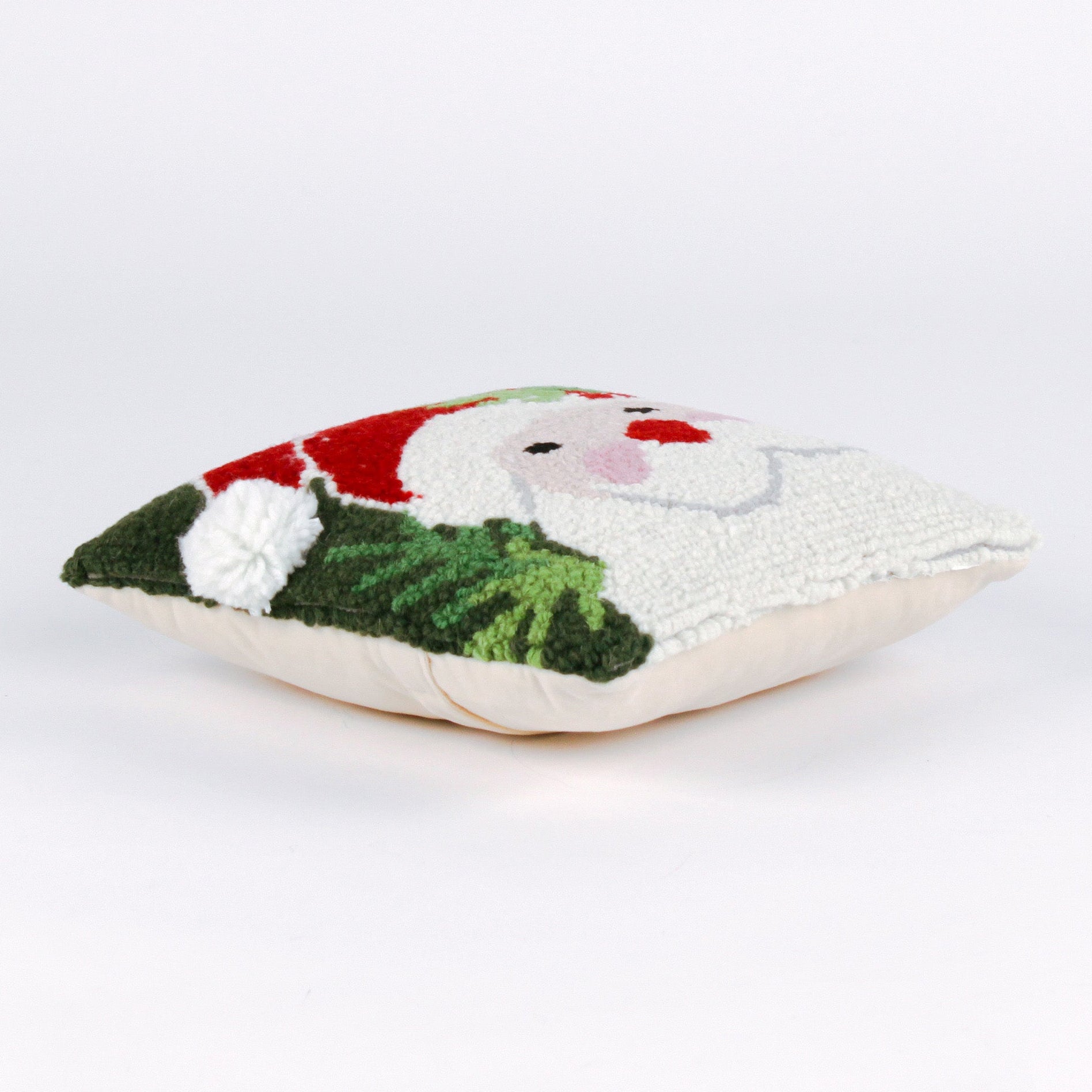 side of a Square Christmas pillow featuring a hooked wool design of Santa Claus with rosy cheeks, a red hat, and green holly leaves on a dark green background.