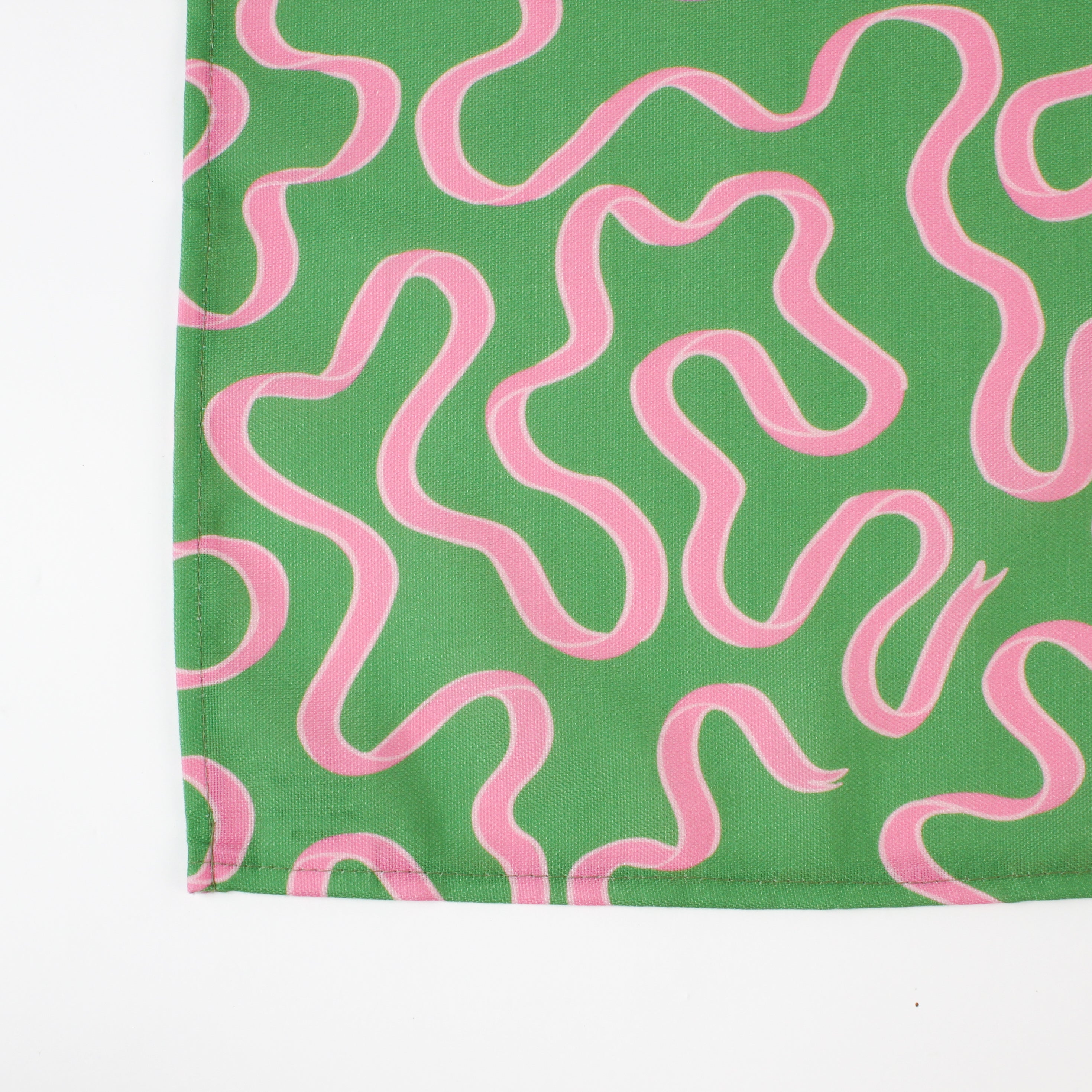 A green table runner with a pink ribbon motif photographed against a white background 
