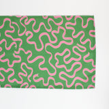 A green table runner with a pink ribbon motif photographed against a white background 