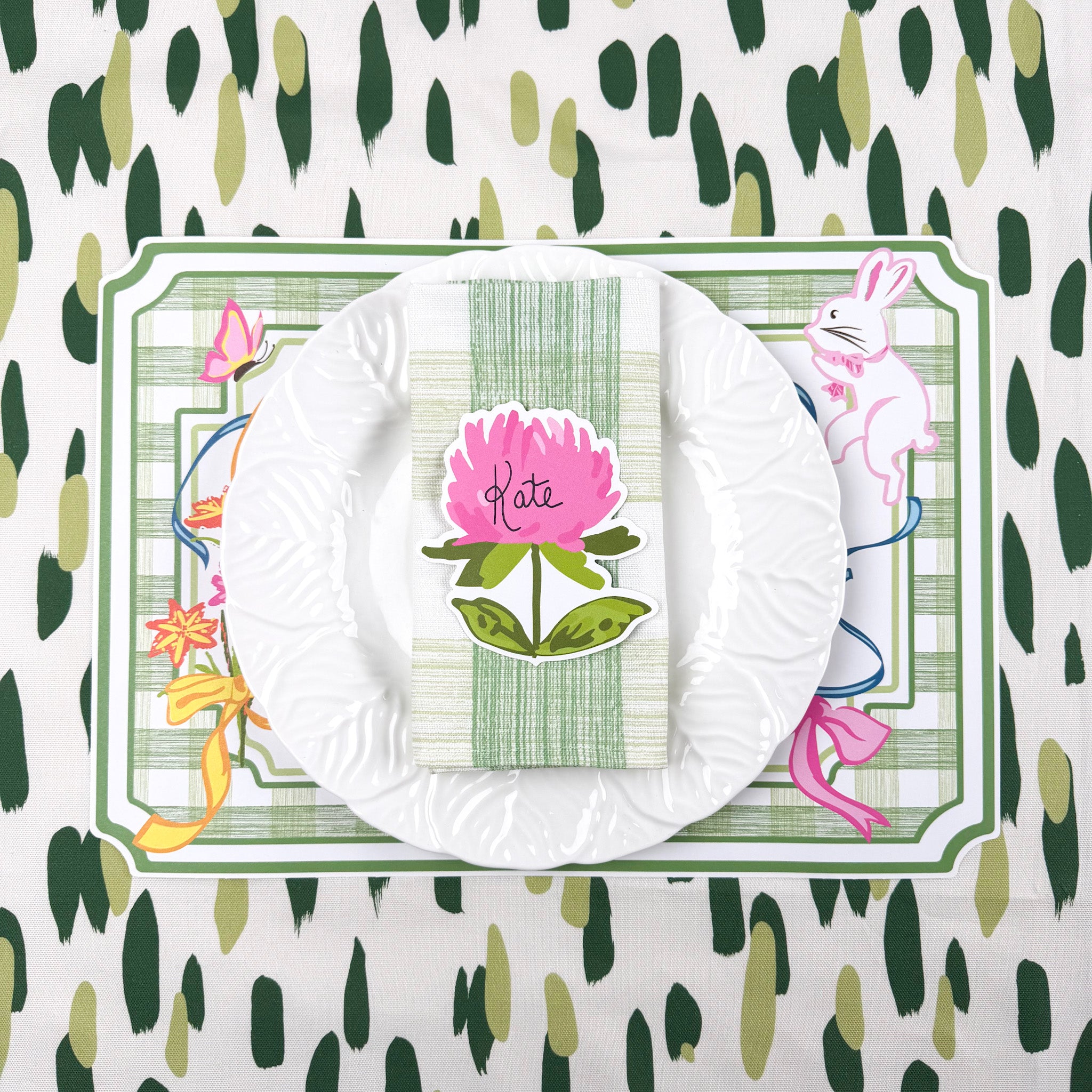 spring Easter paper placemat table setting with white plate, green striped napkin, and floral place card.