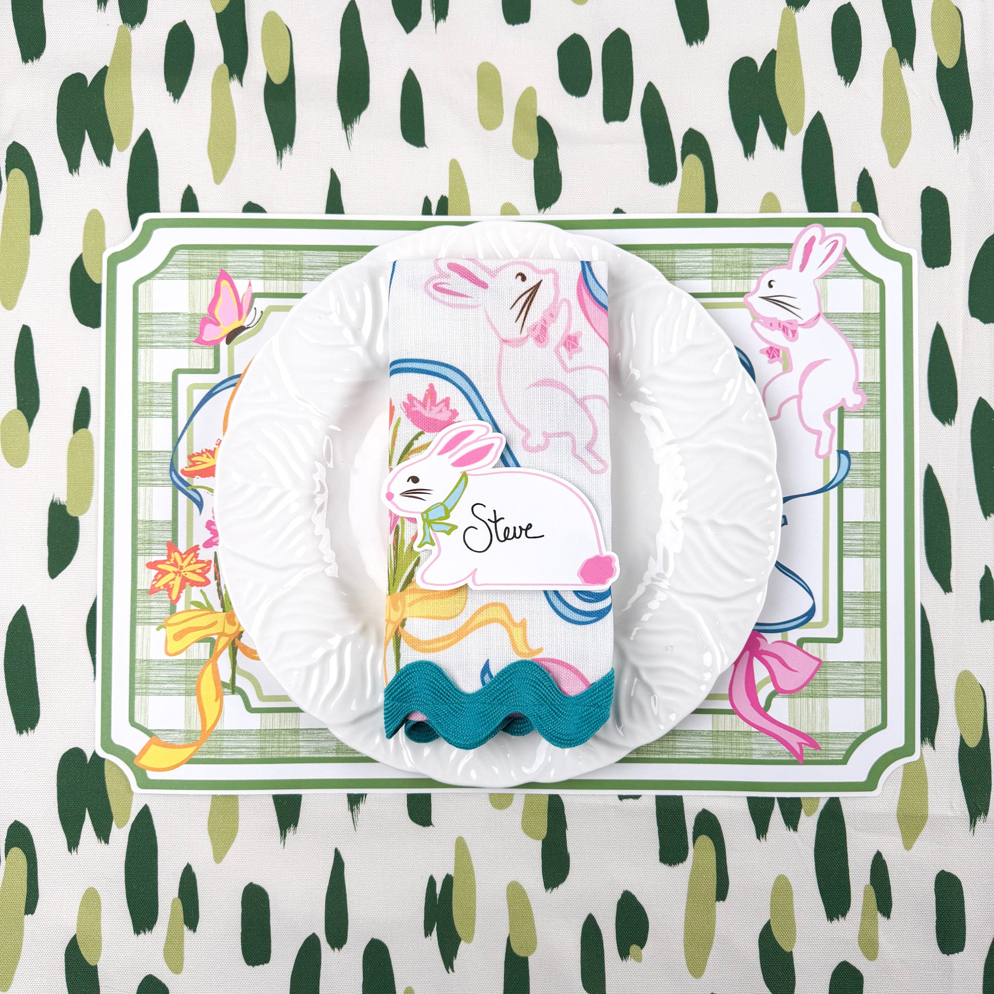 spring Easter paper placemat with bunny place card, white plate, and green striped napkin.