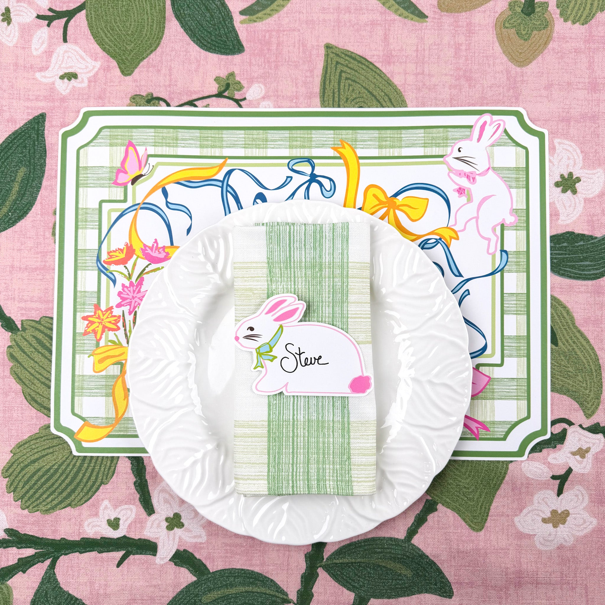 spring Easter paper placemat with bunny place card, white plate, and green striped napkin.
