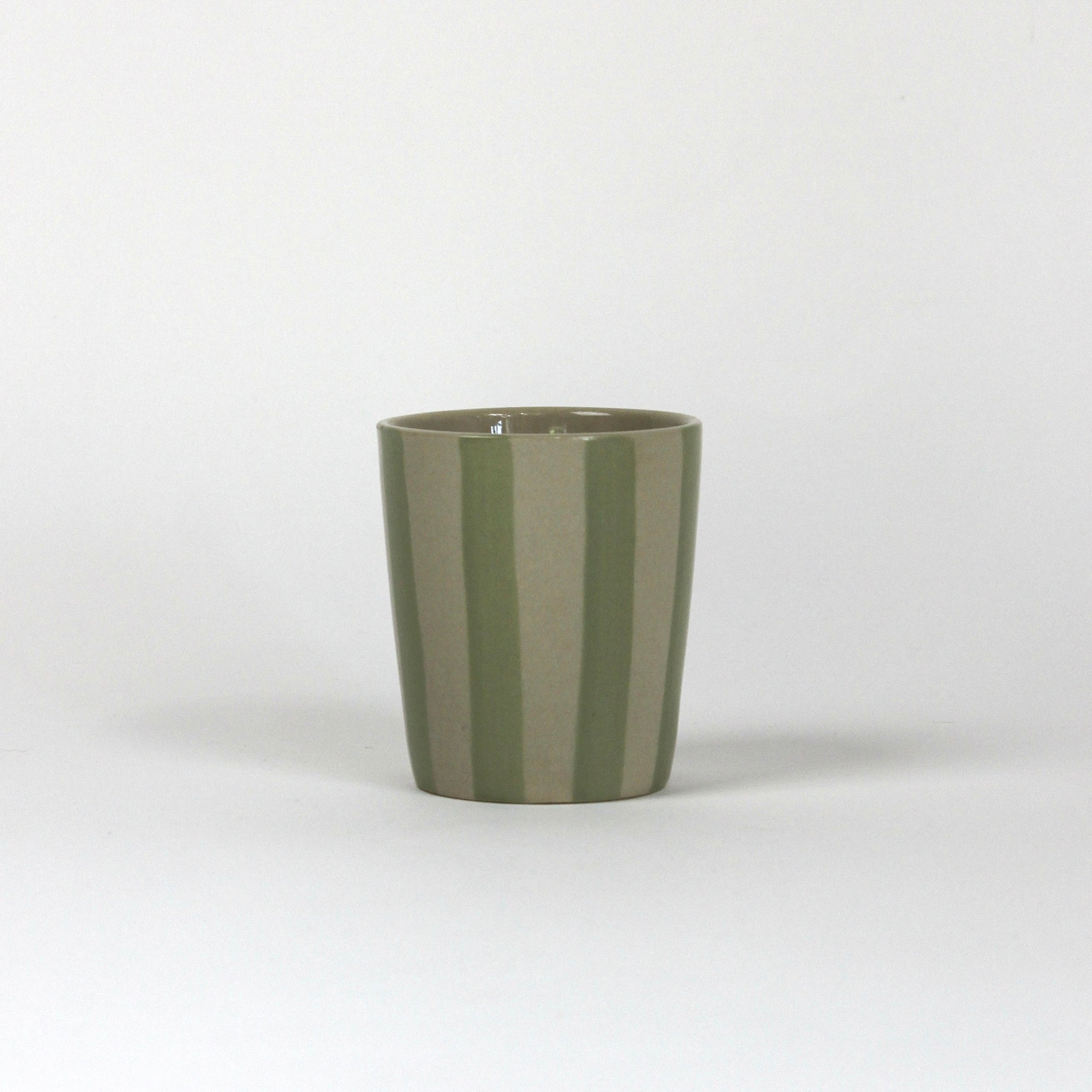 A green striped ceramic cup in on a white background. 