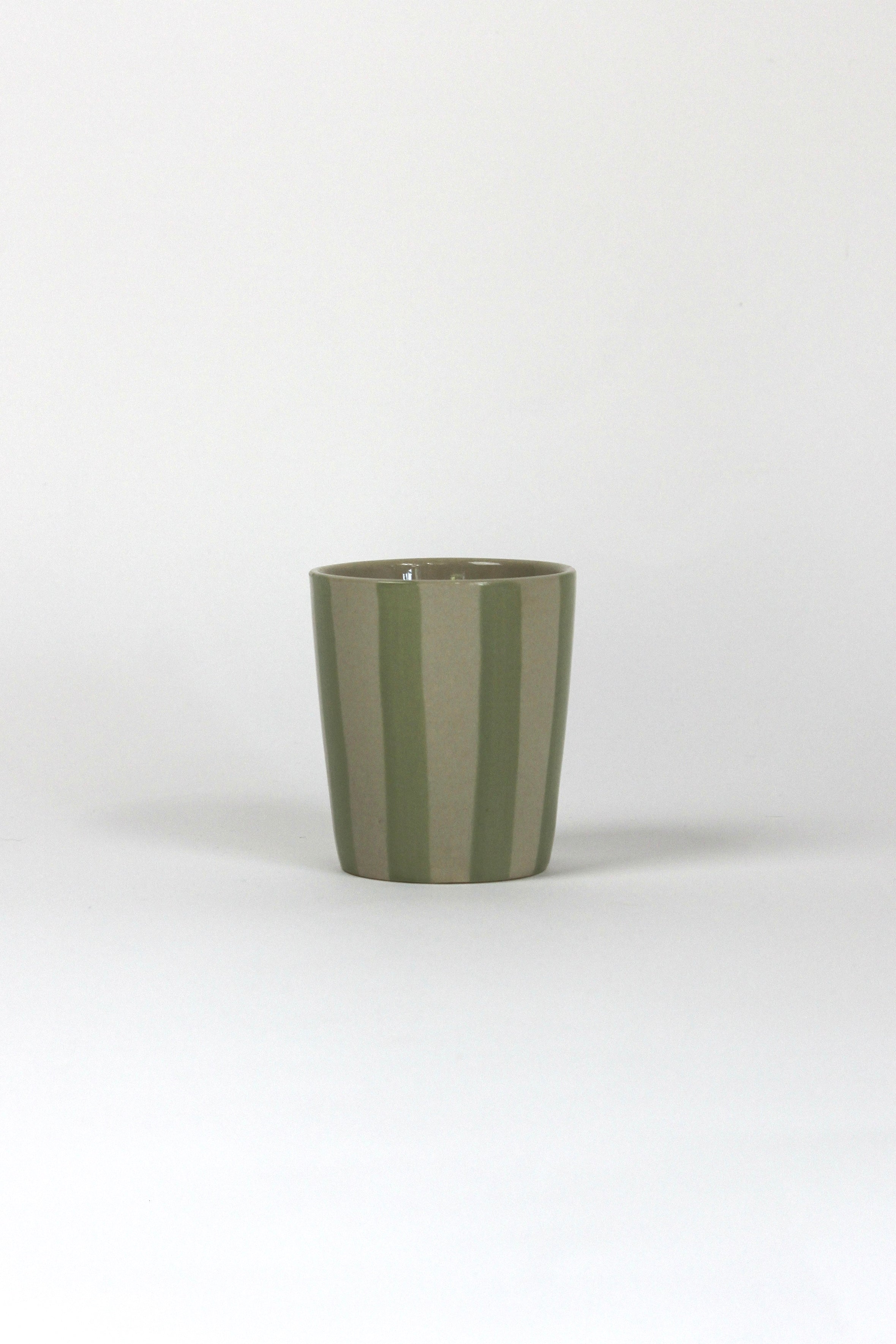 A green striped ceramic cup in on a white background. 