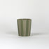 A green striped ceramic cup in on a white background. 