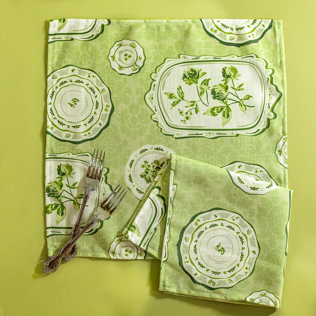 Green vintage plates fabric napkins against a green background.