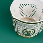 White lattice ceramic planter with green trim and a central green floral medallion design on a green background