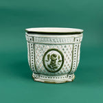 White lattice ceramic planter with green trim and a central green floral medallion design on a green background