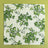A green bunny and strawberry print fabric Easter napkin against a green background. 