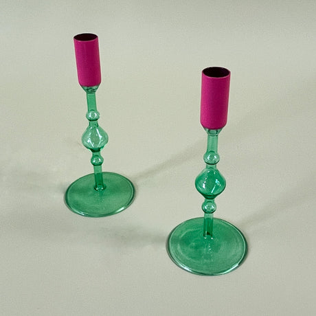 two green glass candle holders with pink tops