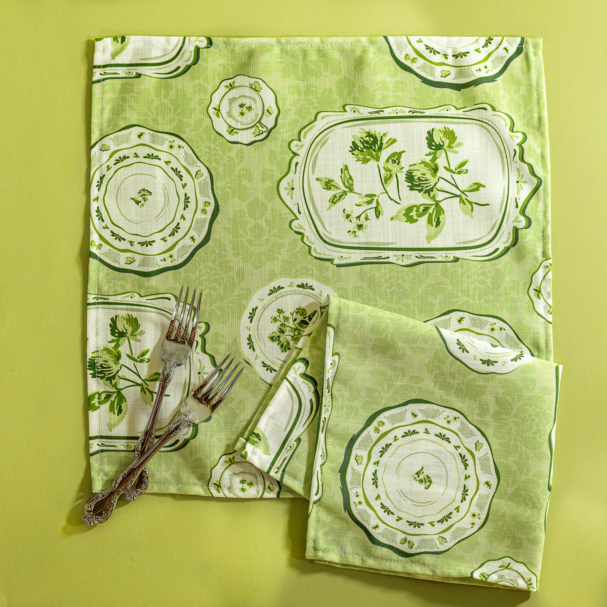 Green vintage plates fabric napkins against a green background. 