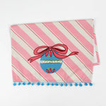 striped pink christmas tea towel with a blue ornament and pink bow central motif on a white background. 
