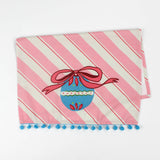 striped pink christmas tea towel with a blue ornament and pink bow central motif on a white background. 