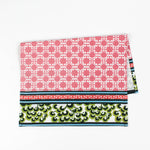 Christmas tea towel featuring a pink lattice pattern with green and white Chinoiserie-inspired borders