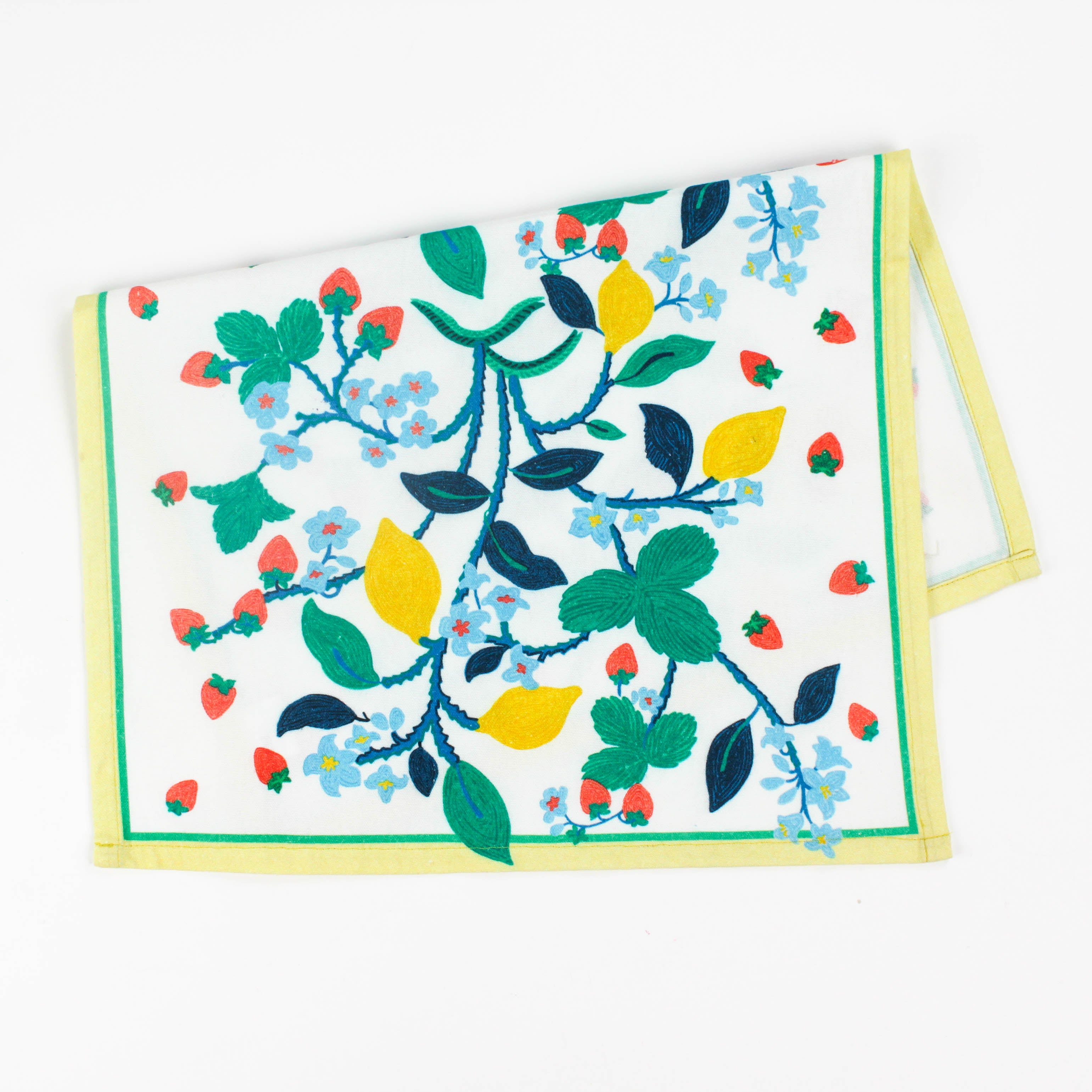 Christmas tea towel featuring a bright botanical design with yellow lemons, red strawberries, and green leaves on a white background bordered with soft yellow and green trim.