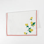 White Christmas tea towel decorated with yellow lemons and green leaves along the edges, bordered by a thin red outline