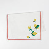 White Christmas tea towel decorated with yellow lemons and green leaves along the edges, bordered by a thin red outline