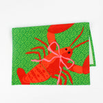 Green Christmas tea towel with a festive red lobster illustration tied with a pink bow