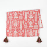 Half-folded Christmas tea towel with a pink and white chinoiserie pagoda pattern, featuring intricate architectural motifs and pink-green tassels on each corner.