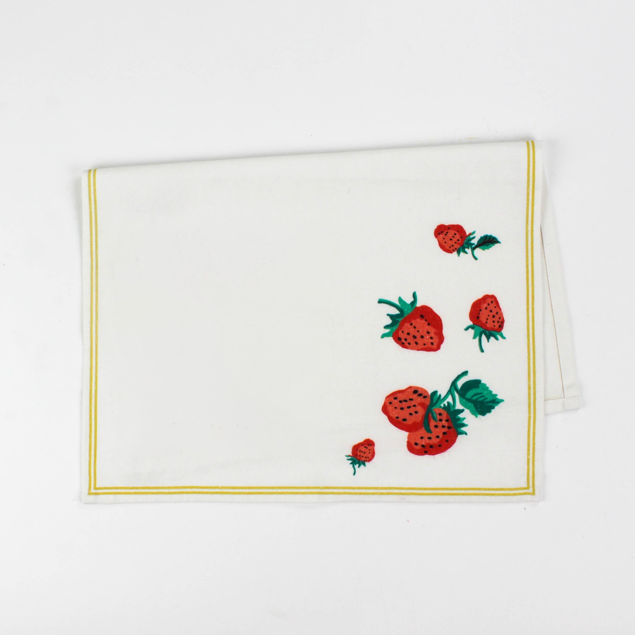 Folded Christmas tea towel with a white background, decorated with strawberries and green leaves in one corner, bordered by a thin yellow trim.