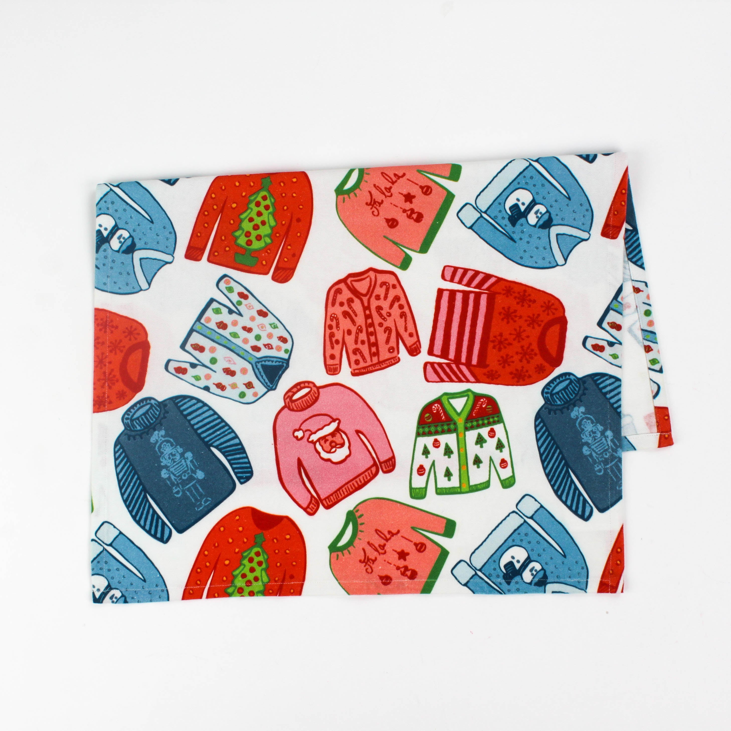 Folded christmas tea towel with colorful holiday sweater pattern in red, green and blue on a white background