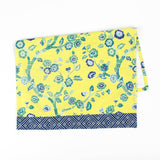 Christmas tea towel with a bright yellow background featuring a blue and green floral chinoiserie pattern