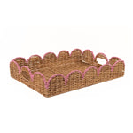 A rectangular woven rattan tray with scalloped edges and pink rope trim on a plain white background.