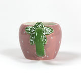 a pink ceramic strawberry mug with a green leafy handle
