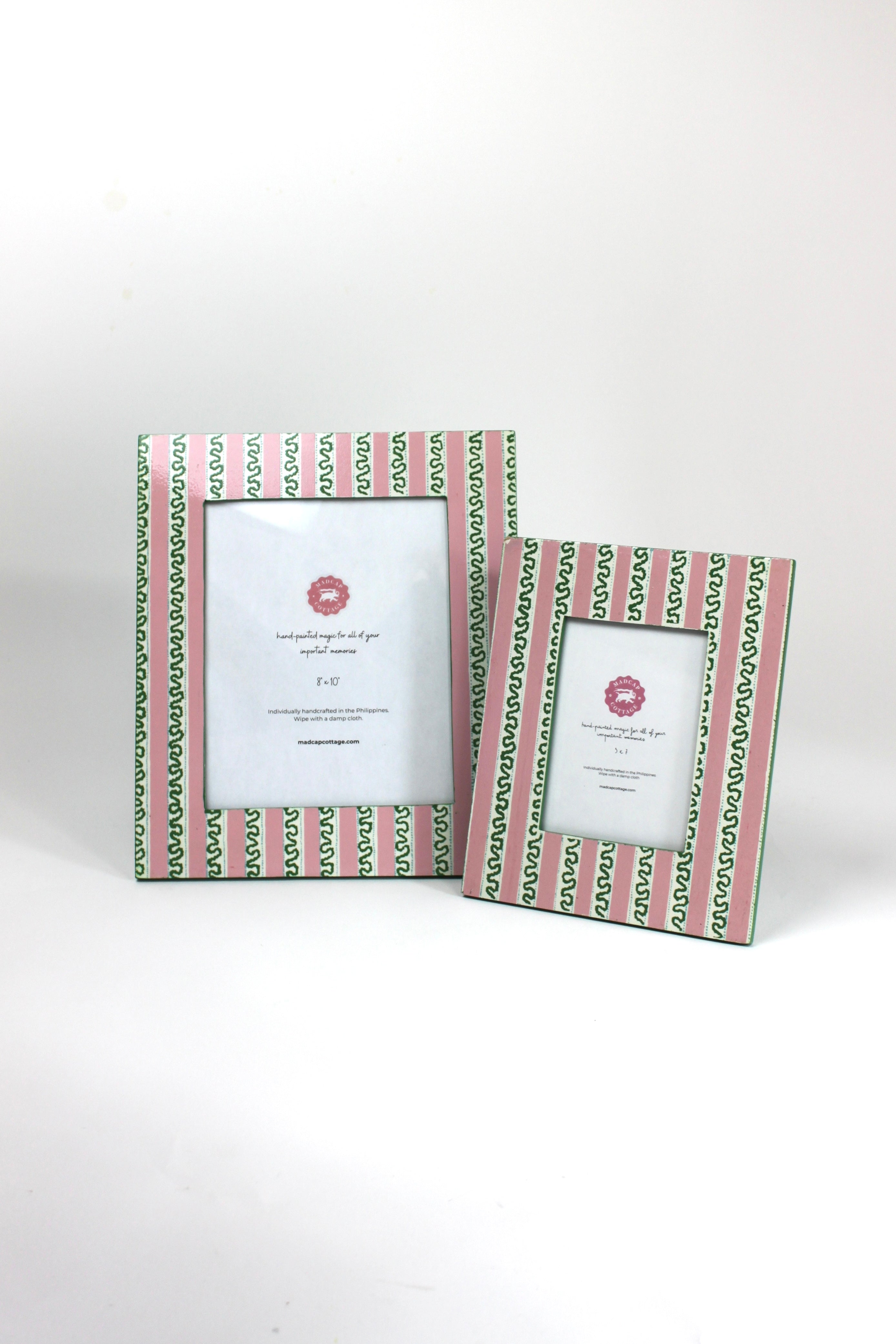 a set of two Hand painted picture frames featuring a pink and white striped motif