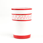 a hand-made white glasses with red stripe and pink pattern in a white background