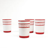 four hand-made white glasses with red stripe and pink pattern in a white background
