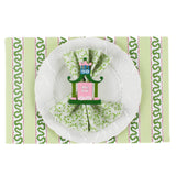 a green paper placemats featuring a striped pattern in a white background. A white plate is placed on top of it with a cloth and a nutcracker napkin ring
