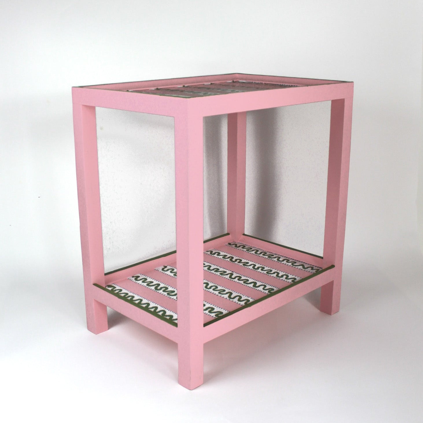 A pink side table with a green and white striped pattern named "Harbor Trail" by madcap cottage
