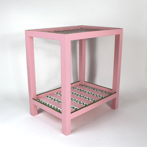 A pink side table with a green and white striped pattern named "Harbor Trail" by madcap cottage