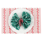 red and pink paper placemats featuring a striped pattern called harbor trail in a white background.  A white plate is placed on top of it with a cloth and a rattan candy cane napkin ring