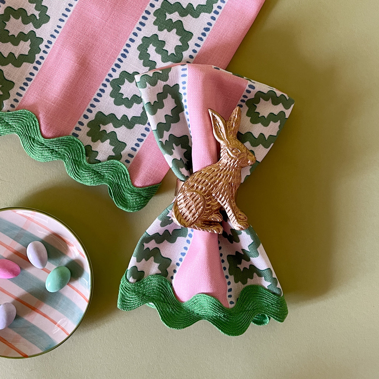 green and pink dinner napkins with a gold bunny napking ring in the striped harbor trail fabric from madcap cottage