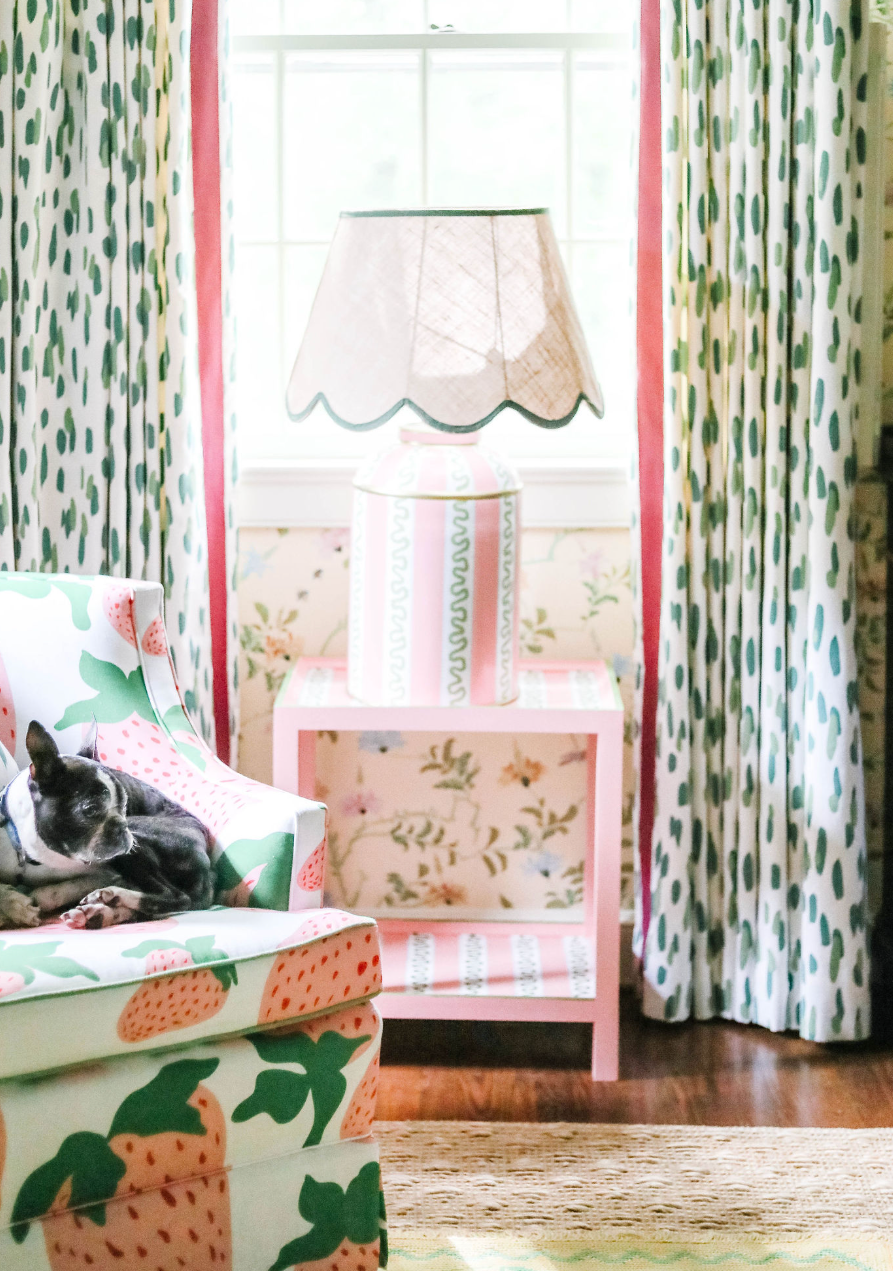 a striped white, pink and green lamp with a scalloped rattan shade with green trim sitting on a pink side table all from madcap cottage