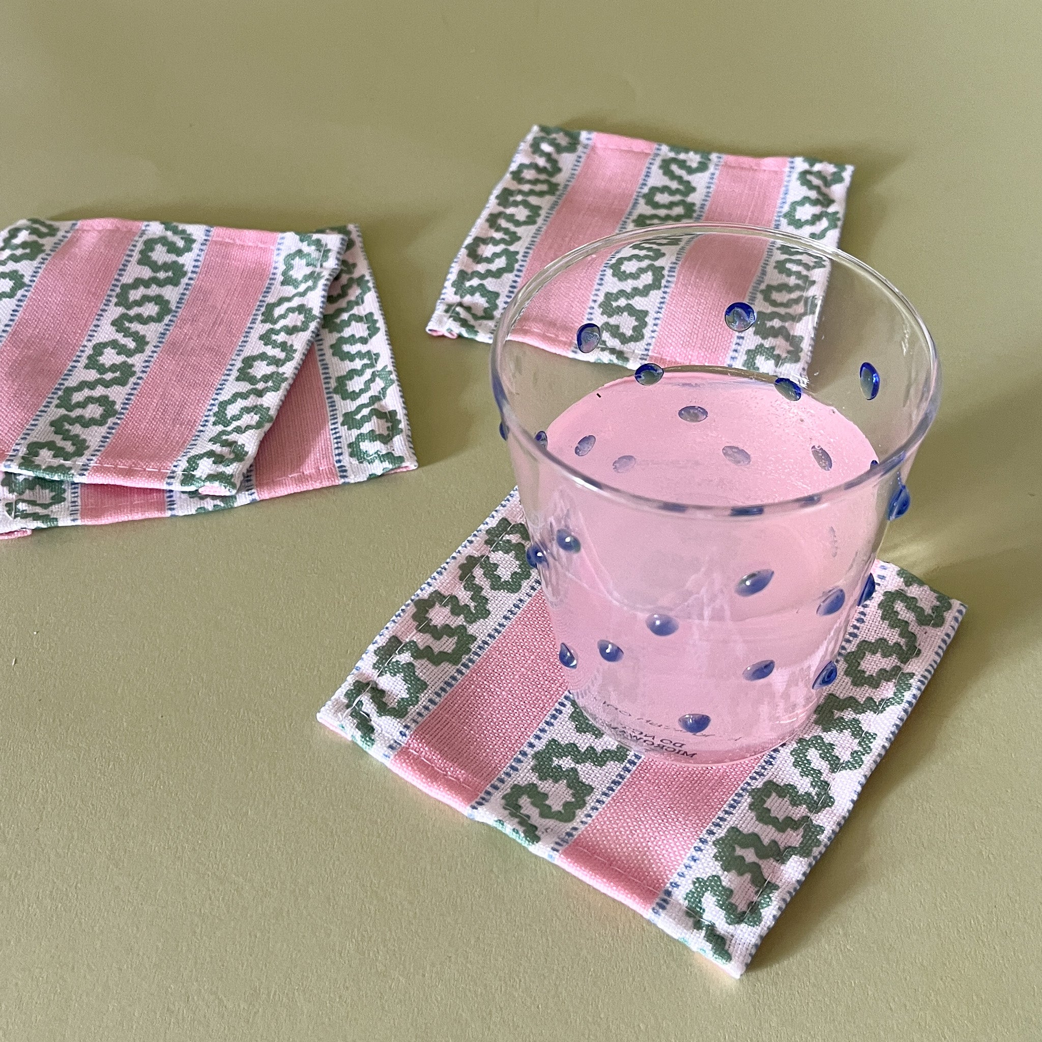 harbor trail pink and green linen cocktail coasters with blue dot drink glass