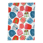 a christmas tea towel featuring a repeating holiday sweater design in red, pink and blue