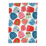 a christmas tea towel featuring a repeating holiday sweater design in red, pink and blue
