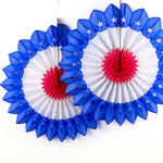 Two red white and blue honeycomb paper fan decorations with patriotic star details hanging against a white background.