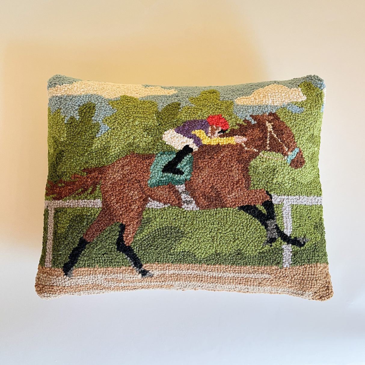 a hooked wool derby day pillow featuring a brown horse and mulitcolor jockey
