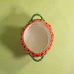the inside of a large red vintage strawberry dish with a green handles and green detail on lid
