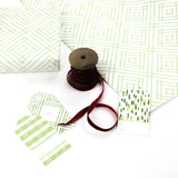 a wrapping paper with a geometric lattice pattern in green with ribbon on wool and gift tags