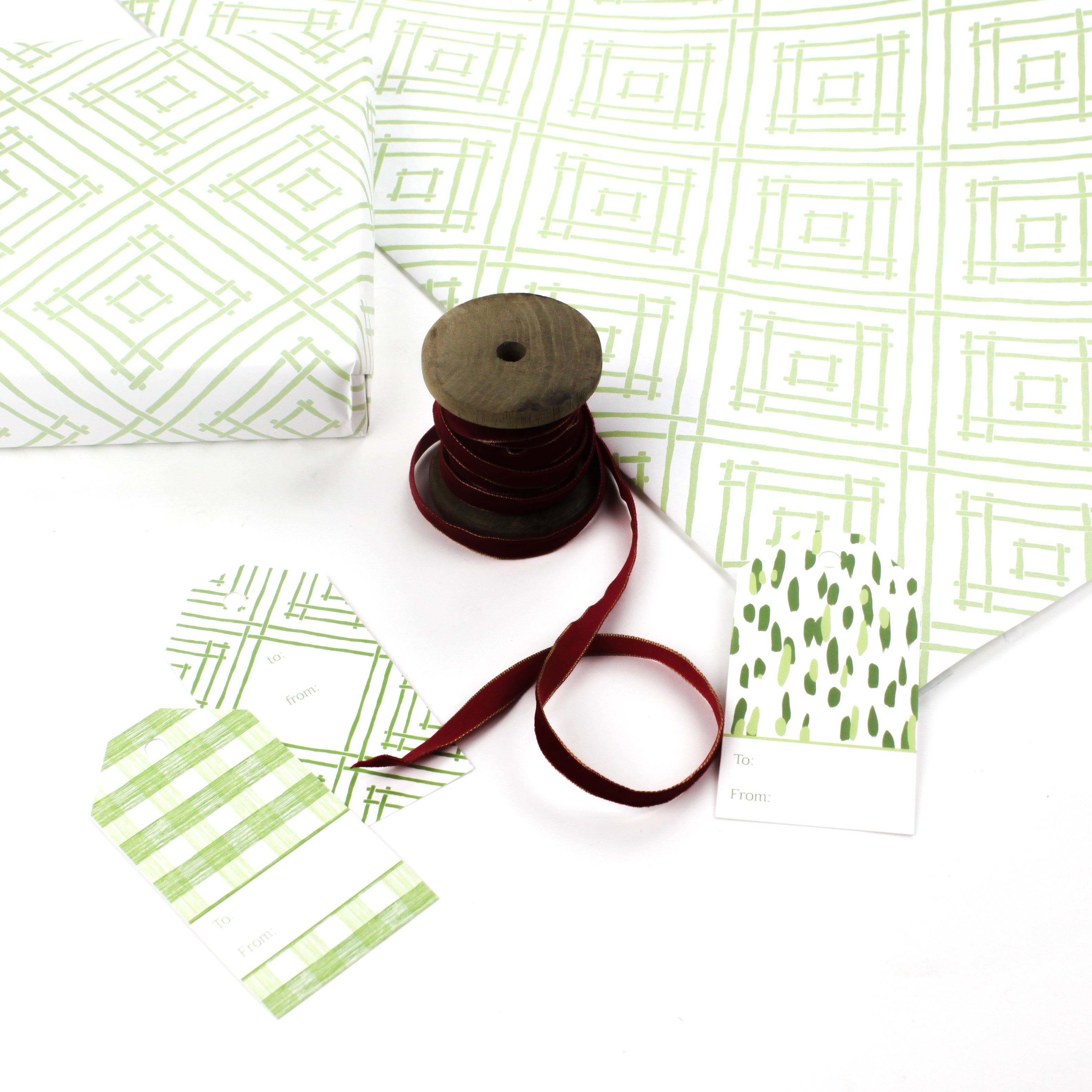 a wrapping paper with a geometric lattice pattern in green with ribbon on wool and gift tags
