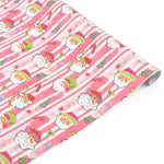 Festive Christmas gift wrap roll featuring cheerful Santa faces, pink stripes, candy canes, and trees.