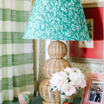 A large rattan lamp with a green lampsade on a blue night stand .