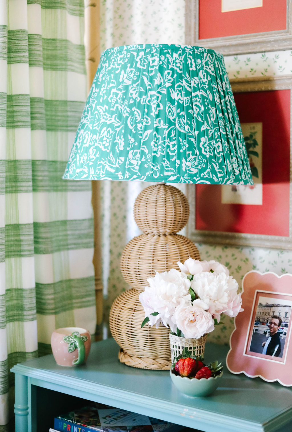 A large rattan lamp with a green lampsade on a blue night stand .