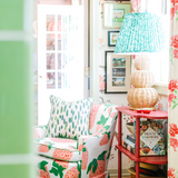 A large rattan lamp with a green lampsade on a red bookshelf in a floral living room scene